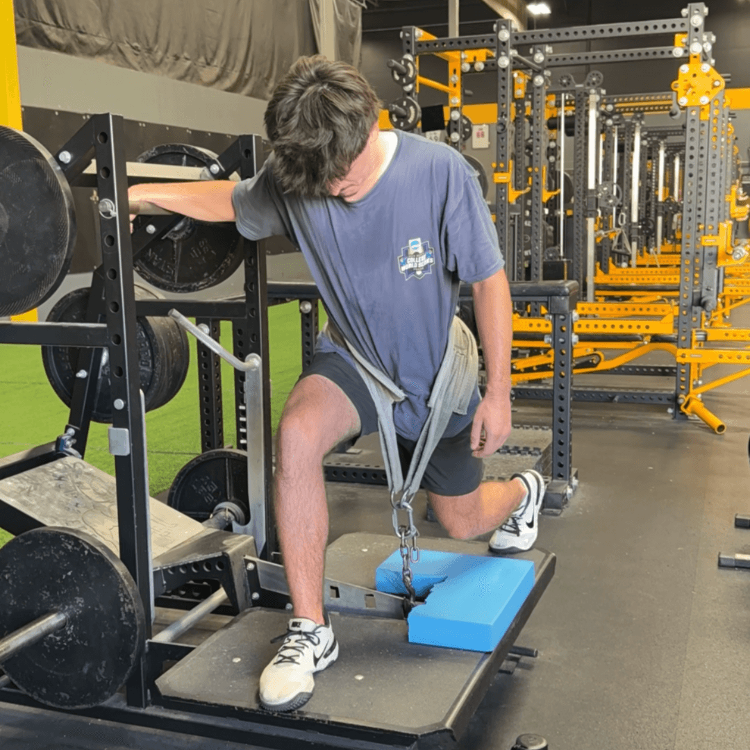 Baseball athlete performing a loaded split-stance lower-body exercise during rehabilitation