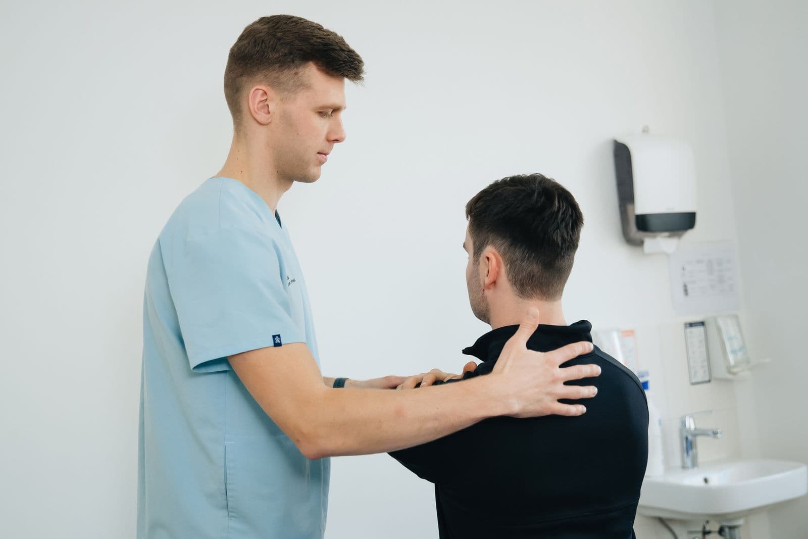 A physiotherapist using hands-on shoulder treatment during a rehabilitation session