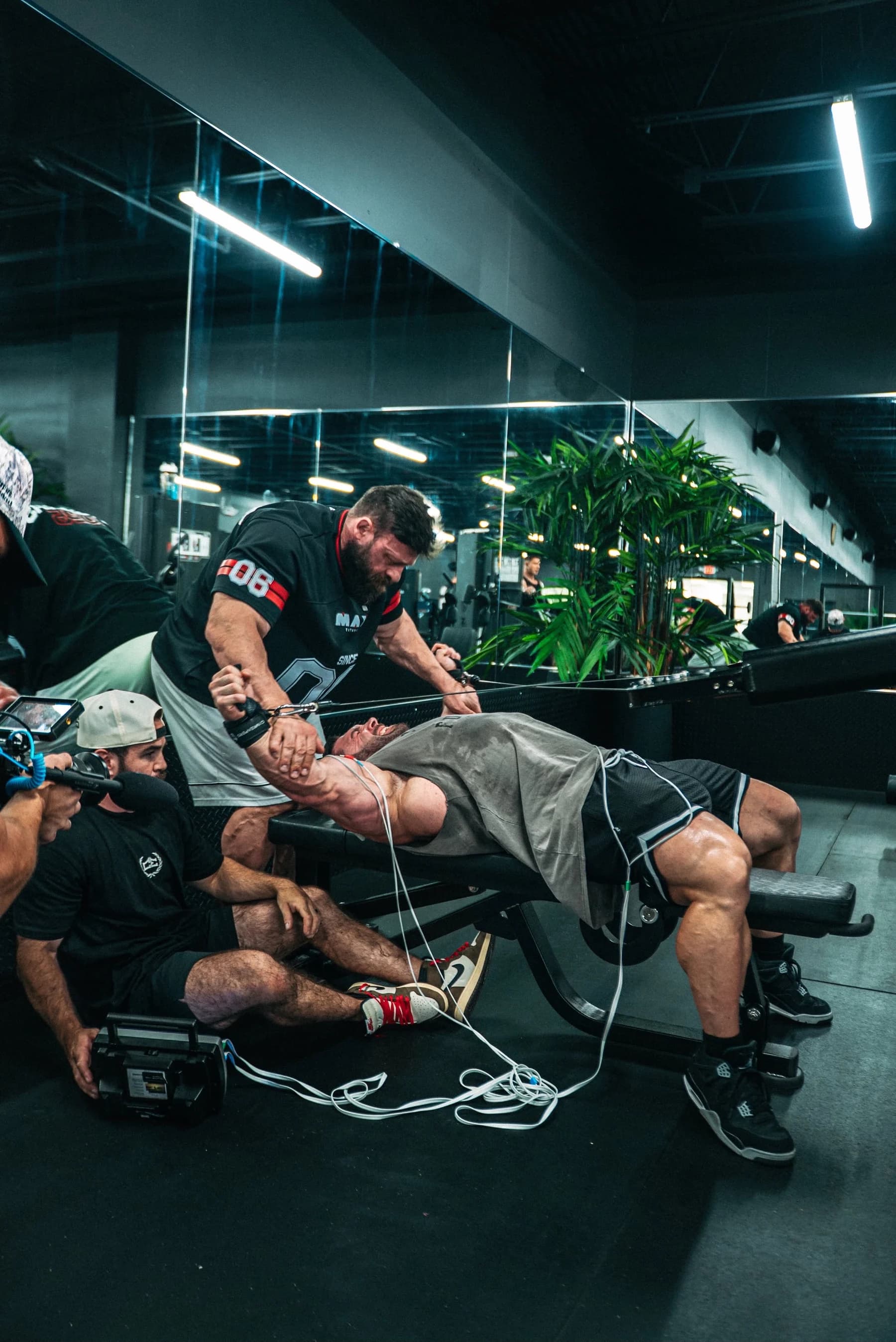 Bodybuilding athlete receiving hands-on care and neuromuscular stimulation on the gym floor