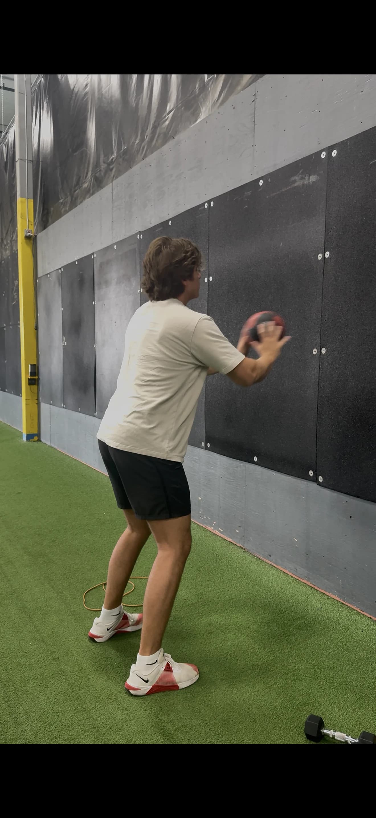 Baseball player performing an explosive medicine-ball wall throw during plyometric loading